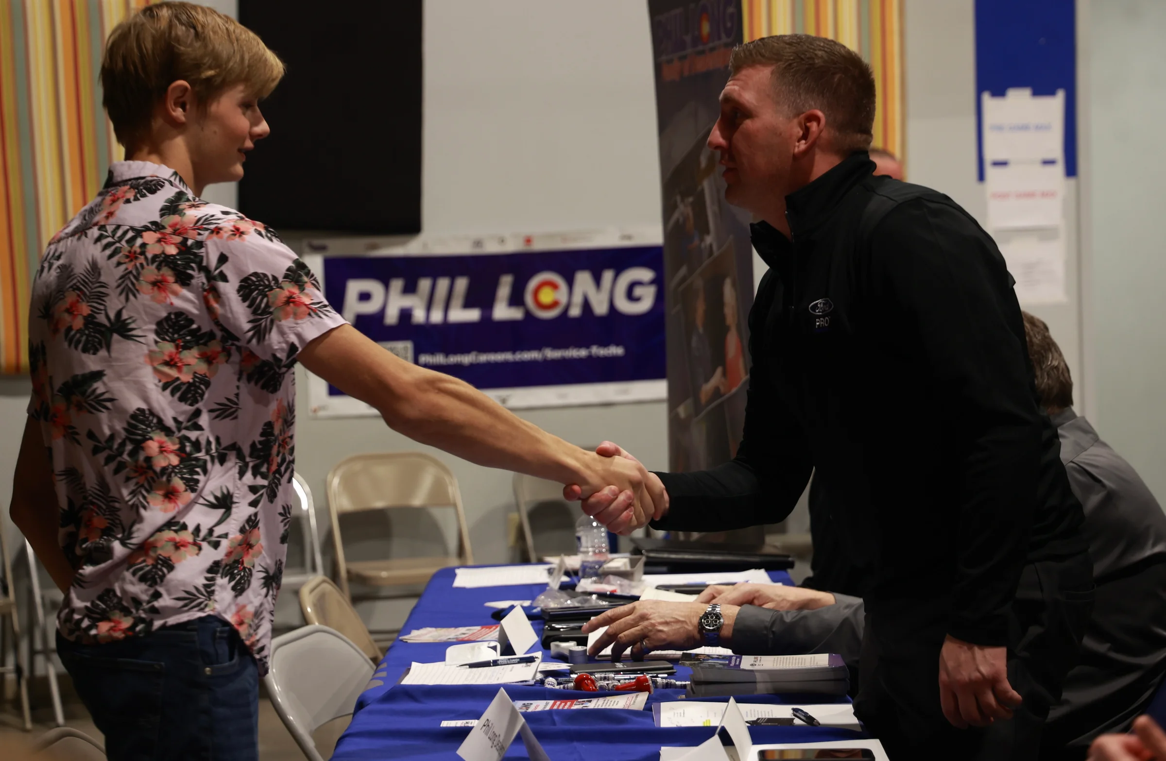 A student shakes hands with a hiring employer at the Phil Long table during a Jumpstart Draft Day.